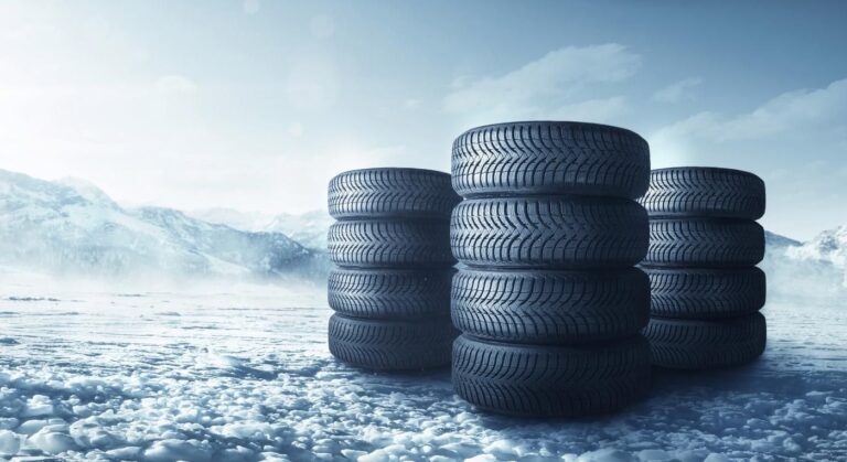 Foto con tres columnas de neumáticos apilados sobre la nieve.