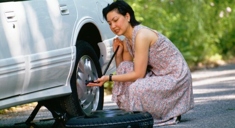 Foto de una mujer reparando el pinchazo de su auto.